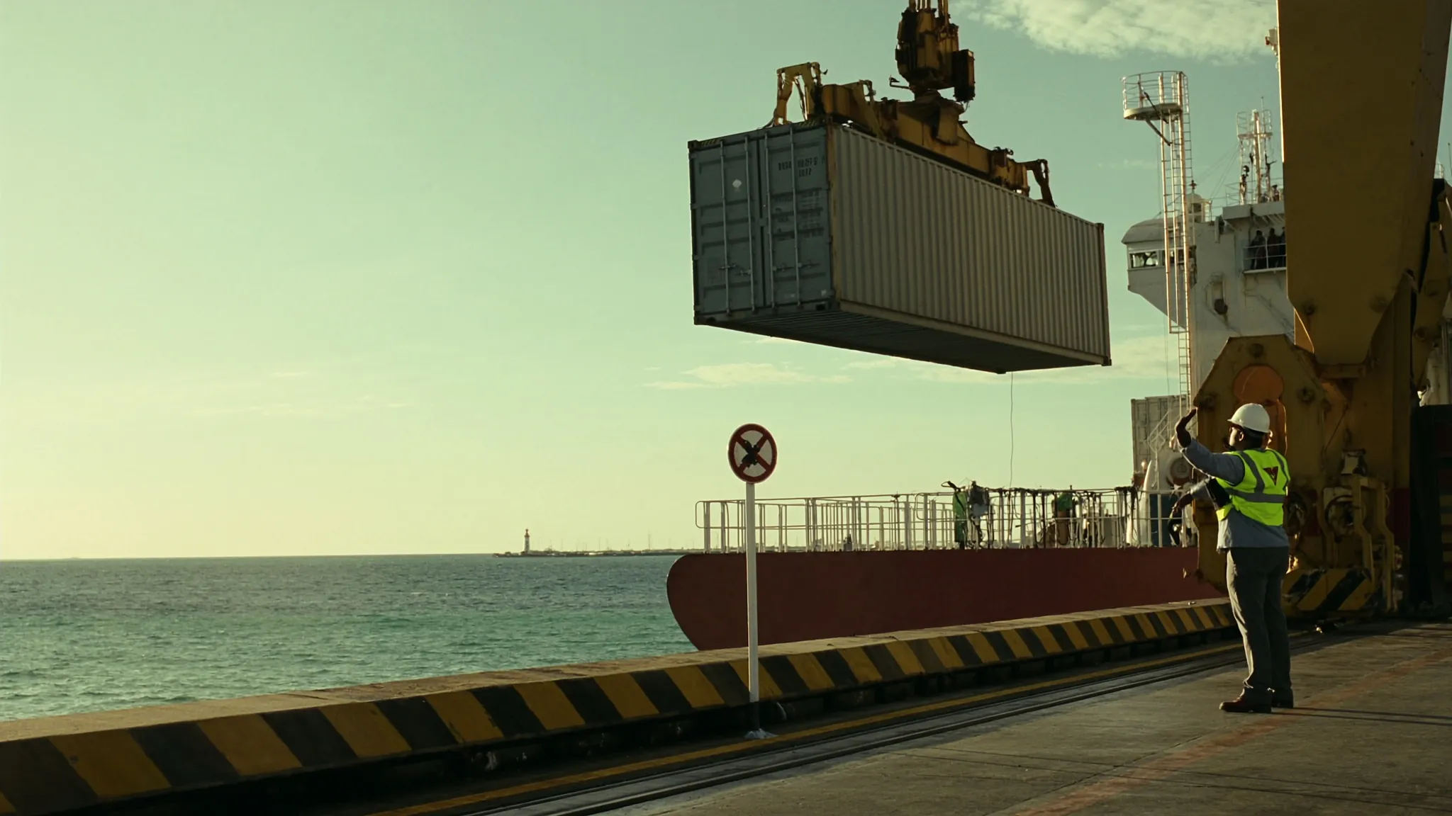 Señalero guía desde fuera de la zona de exclusión el izaje de un contenedor en una terminal portuaria